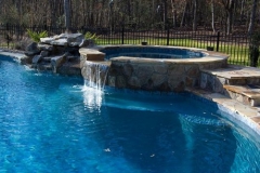 spa with waterfall into pool